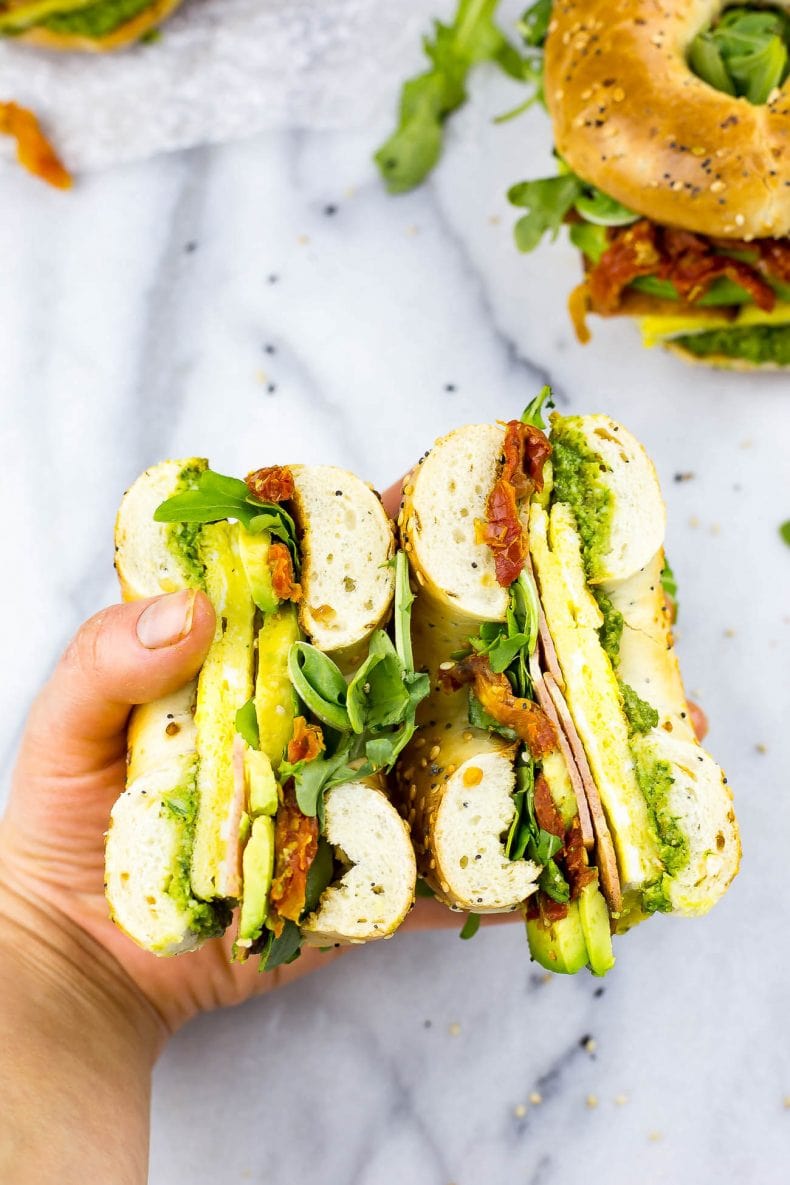 These Pesto Bagel Breakfast Sandwiches come fully loaded with scrambled eggs, turkey bacon, arugula, sundried tomatoes, avocado and a quick basil pesto in between an everything bagel!
