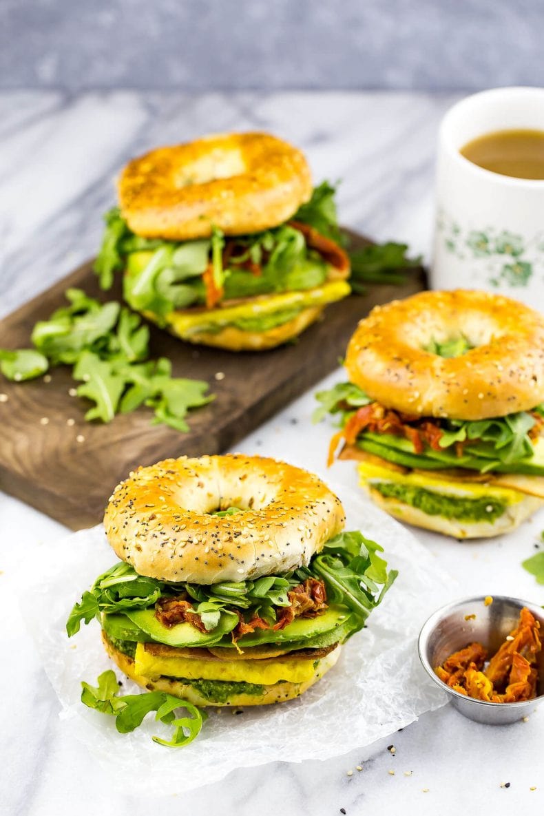 These Pesto Bagel Breakfast Sandwiches come fully loaded with scrambled eggs, turkey bacon, arugula, sundried tomatoes, avocado and a quick basil pesto in between an everything bagel!
