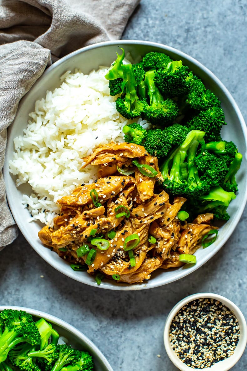 One bowl filled with white rice, chicken teriyaki and steamed broccoli garnished with sesame seeds and green onions.