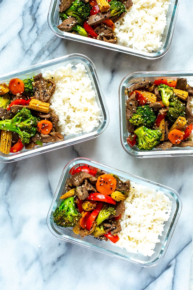 Four meal prep containers, each containing beef stir fry with a side of white rice.