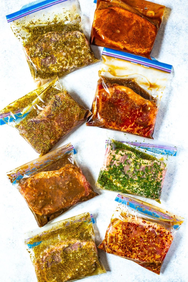 8 different freezer bags, each containing a different kind of marinated steak.