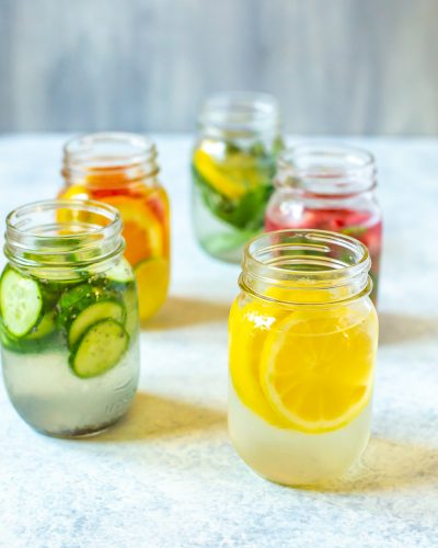 Lemon Water 5 Ways in mason jars. Lemon and cucumber varieties up front.