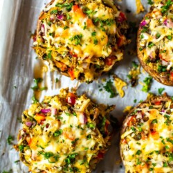 Stuffed portobello mushrooms on a sheet pan lined with parchment paper.