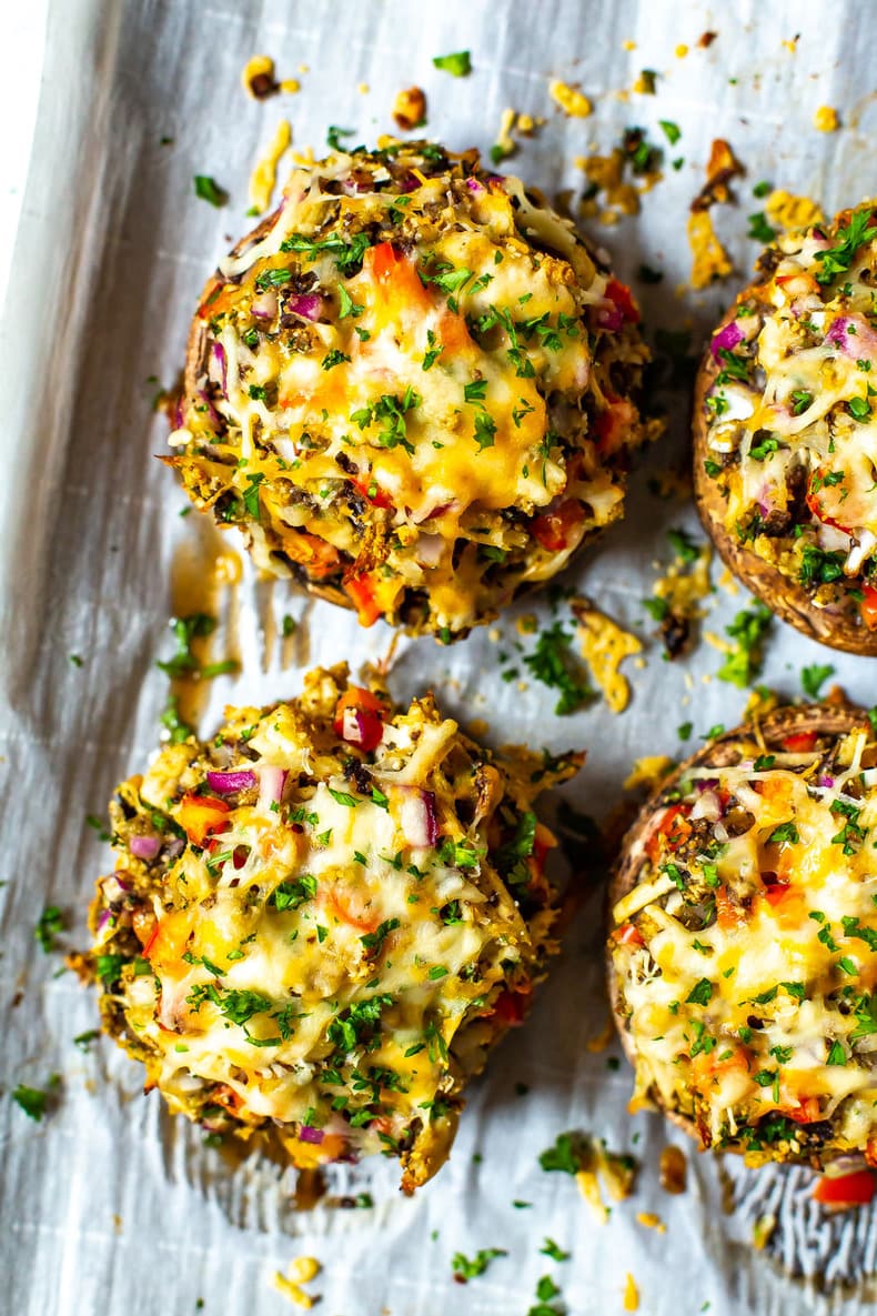 Stuffed portobello mushrooms on a sheet pan lined with parchment paper.