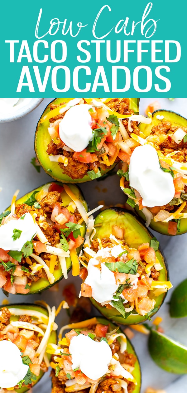 These Low Carb Taco Stuffed Avocados are filled with seasoned ground turkey and topped with pico de gallo, cheese and sour cream - they're a delicious twist on tacos! #lowcarb #stuffedavocados