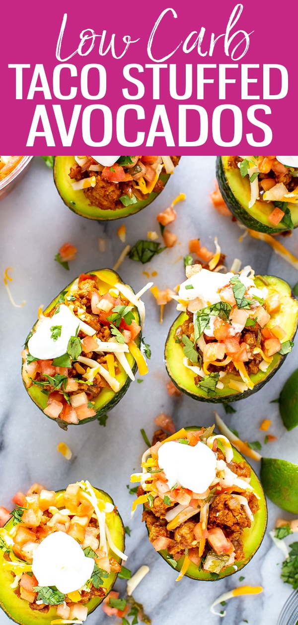 These Low Carb Taco Stuffed Avocados are filled with seasoned ground turkey and topped with pico de gallo, cheese and sour cream - they're a delicious twist on tacos! #lowcarb #stuffedavocados