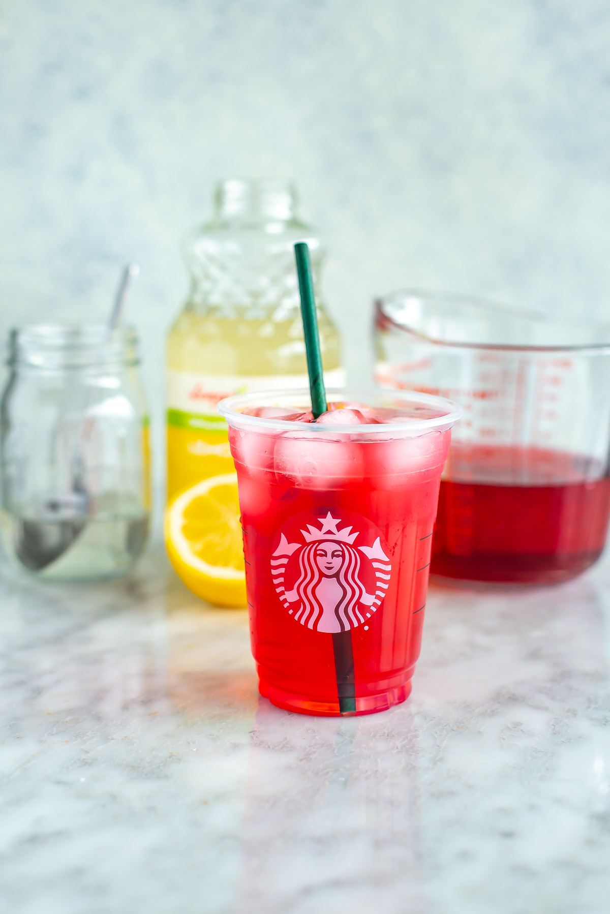 A glass of homemade Starbucks passion tea lemonade with the ingredients placed behind it.