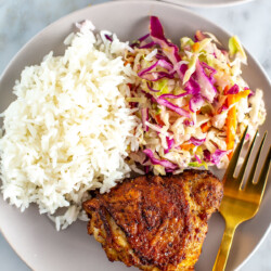 Air fryer chicken thighs with coleslaw and rice on a plate