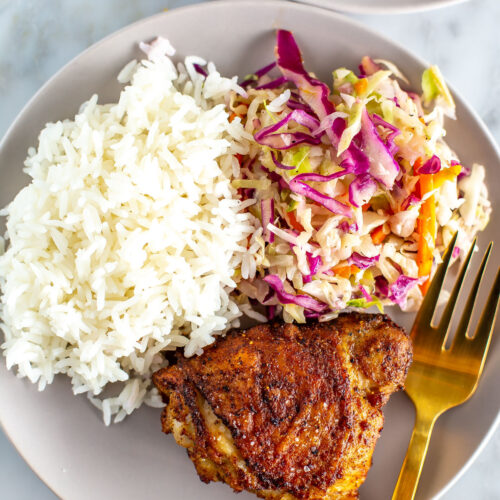 Air fryer chicken thighs with coleslaw and rice on a plate