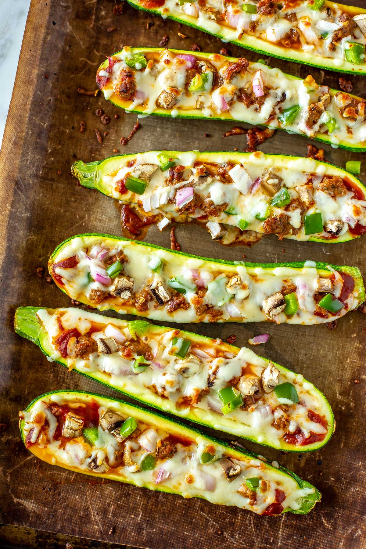 A close-up of zucchini pizza boats on a baking sheet.