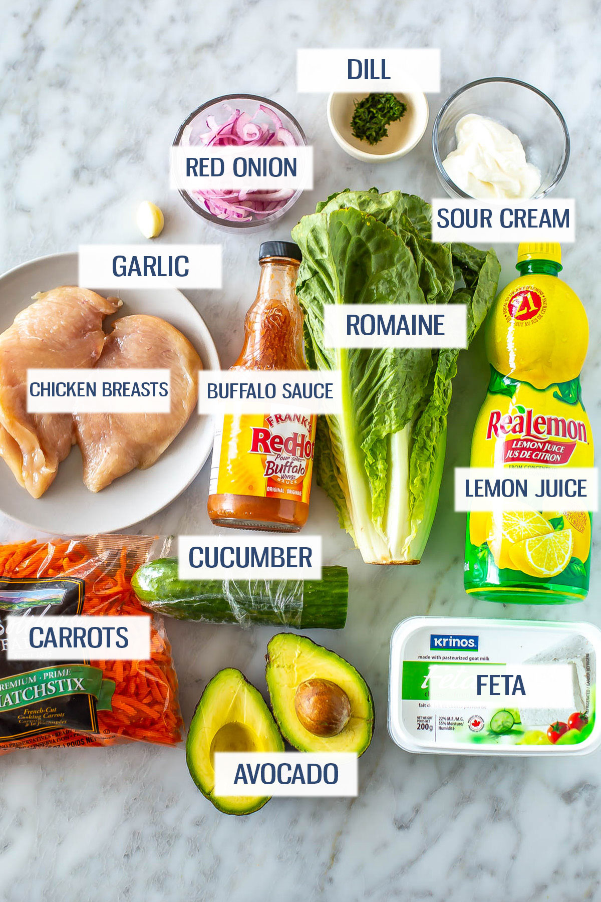Ingredients for buffalo chicken salad: chicken breasts, garlic, red onion, dill, sour cream, carrots, buffalo sauce, romaine, lettuce juice, cucumber, avocado, and feta.