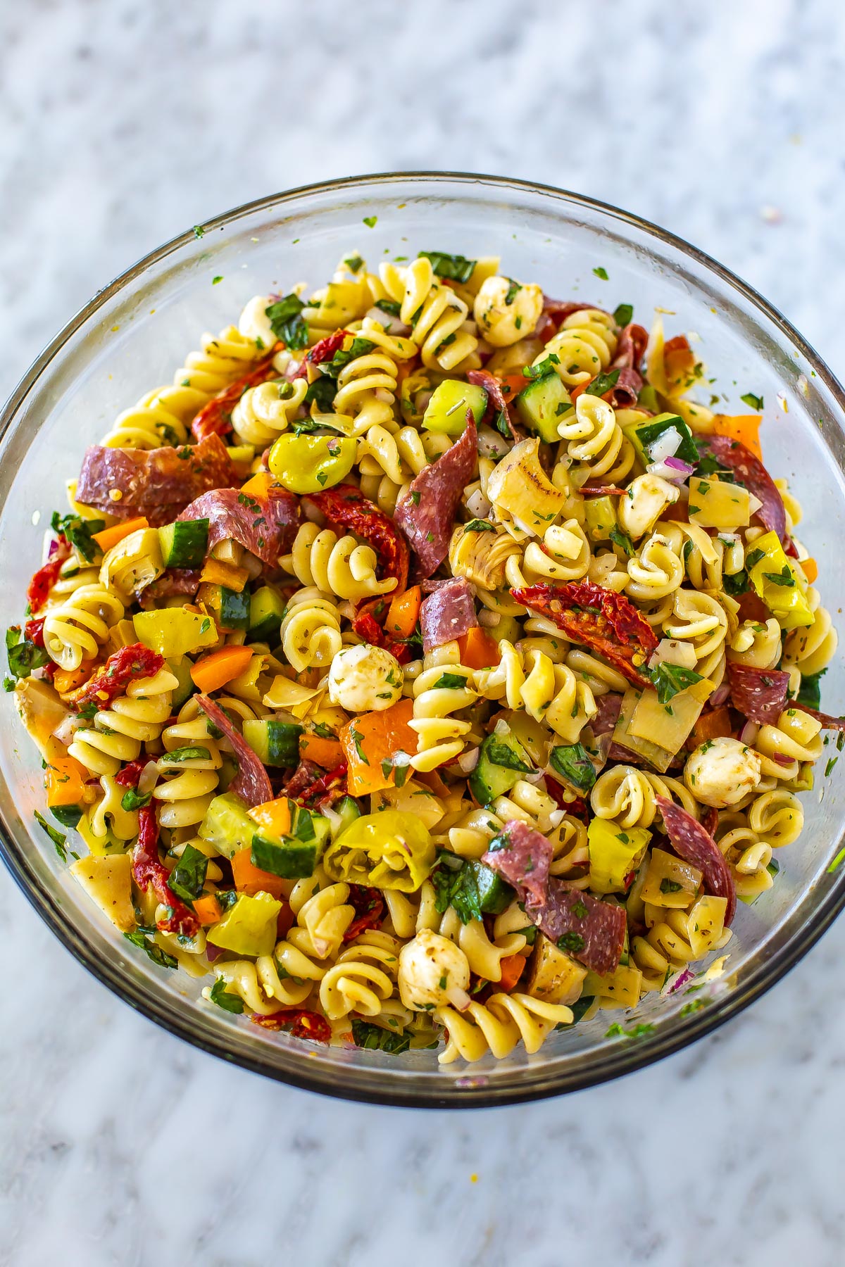 A big bowl filled with Italian pasta salad.