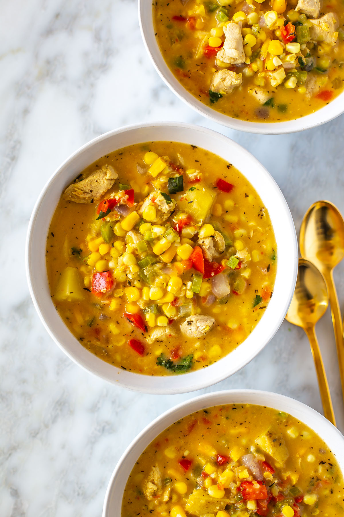 Three bowls each filled with chicken corn chowder.