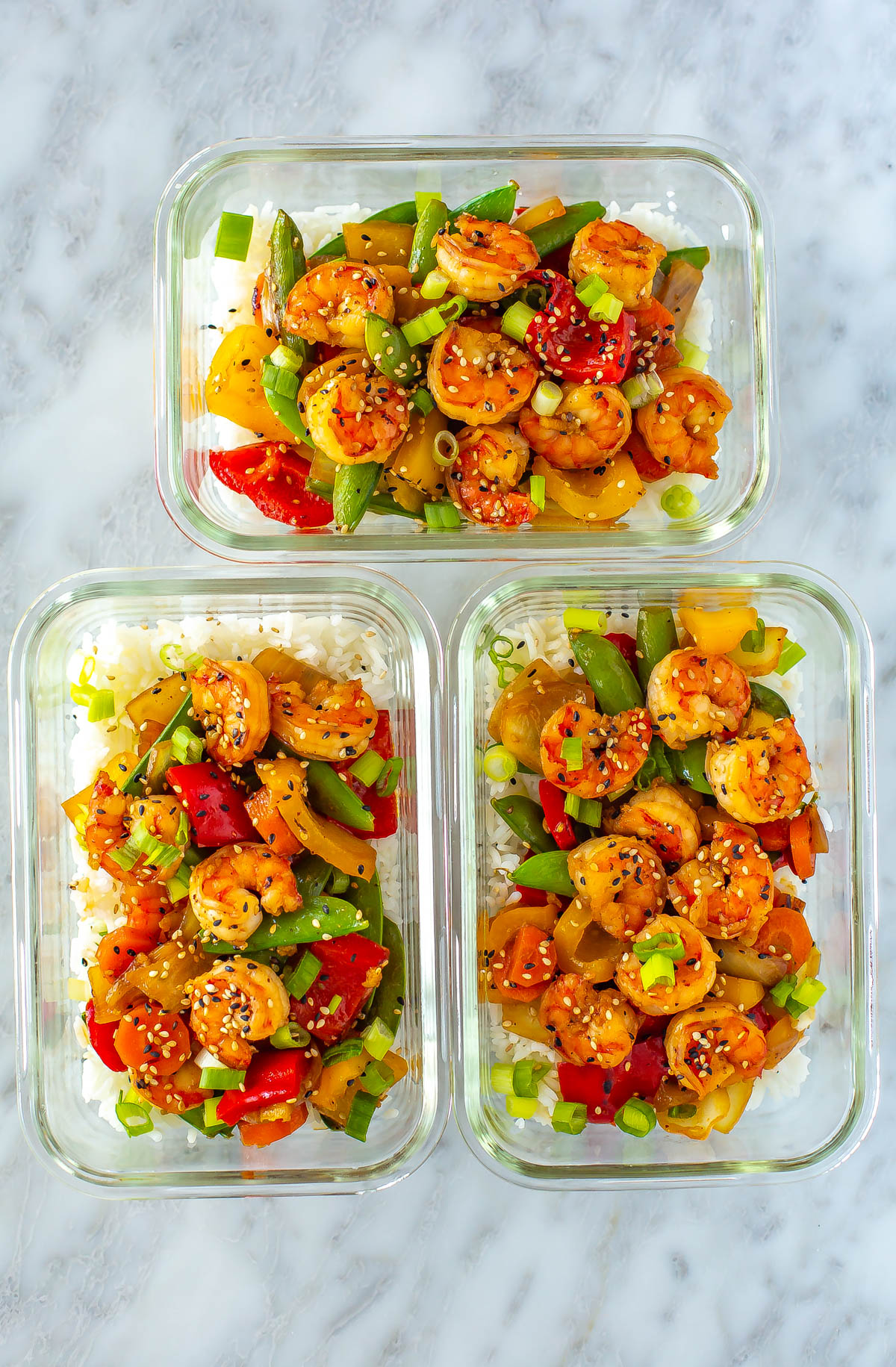 Three glass meal prep containers each filled with rice and honey garlic shrimp stir fry.
