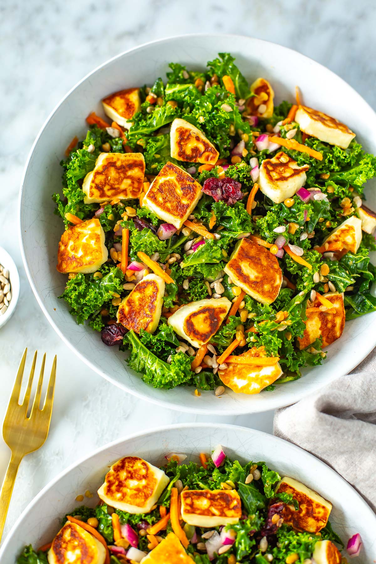 A close-up of a bowl of kale salad topped with halloumi cheese.