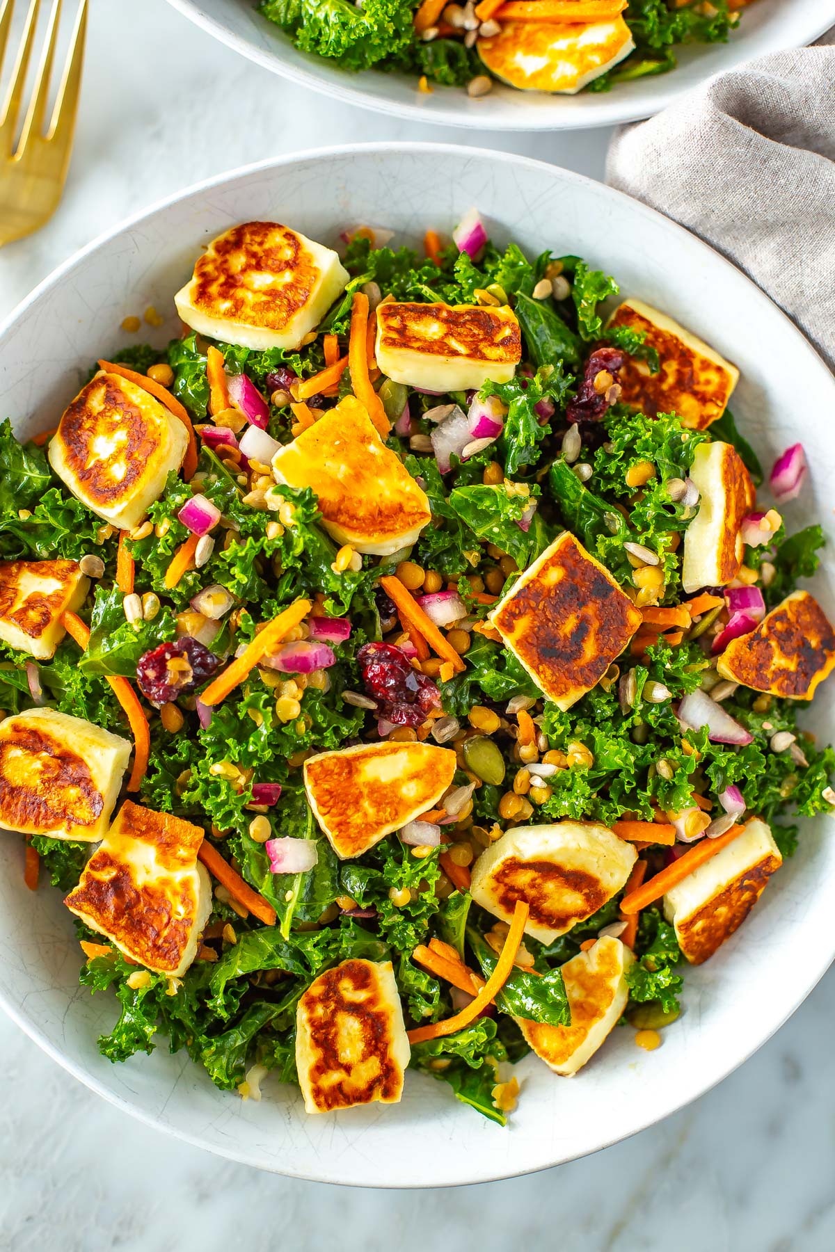 A close-up of a bowl of kale salad topped with halloumi cheese.