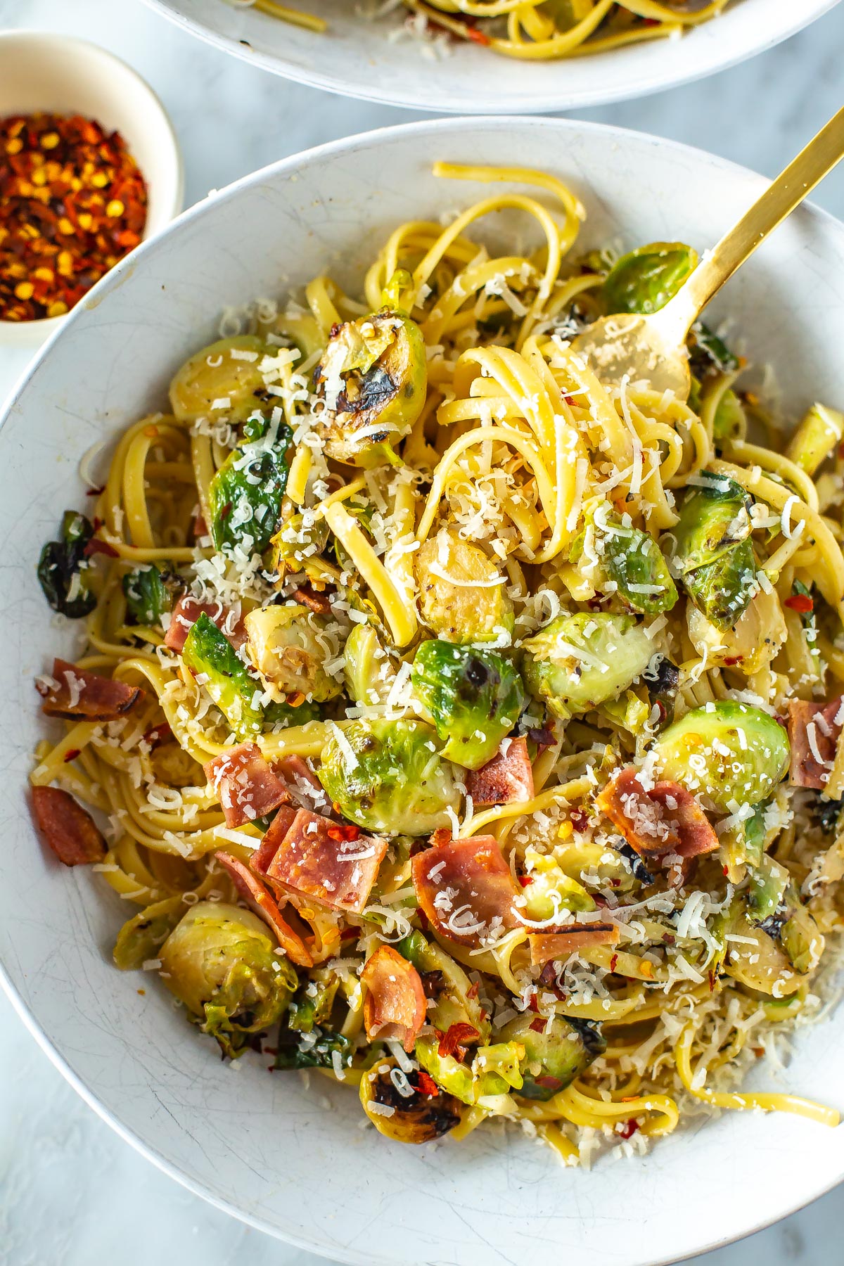 A close-up of a bowl of creamy brussels sprouts pasta with bacon.