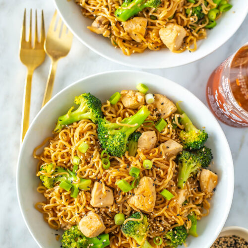 Two bowls of chicken ramen stir fry topped with sesame seeds.