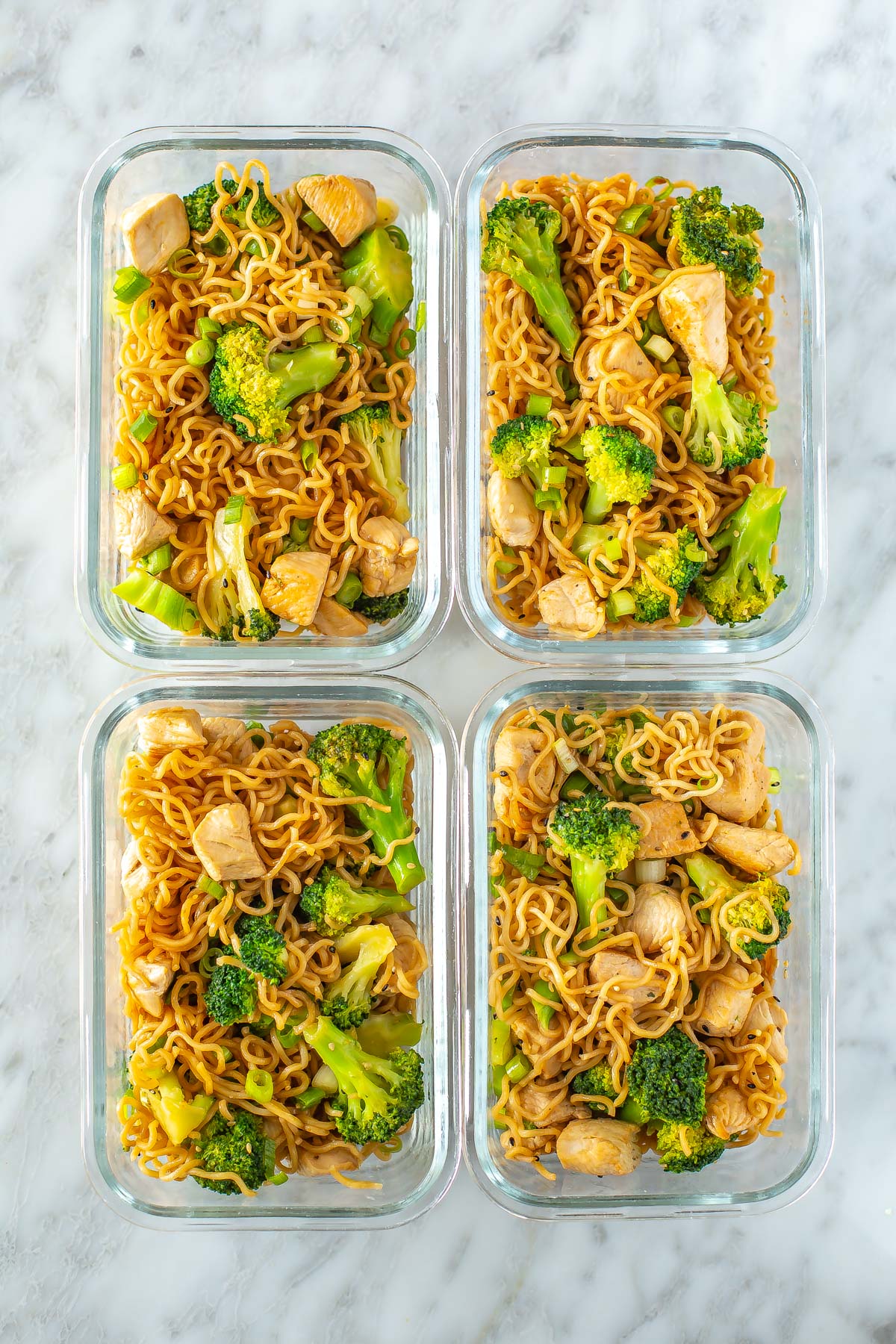 Four meal prep containers, each with a serving of chicken ramen stir fry inside.