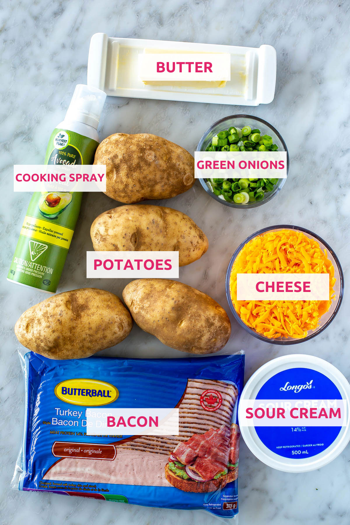 Ingredients for air fryer baked potatoes: potatoes, butter, cooking spray, green onions, cheese, bacon and sour cream.