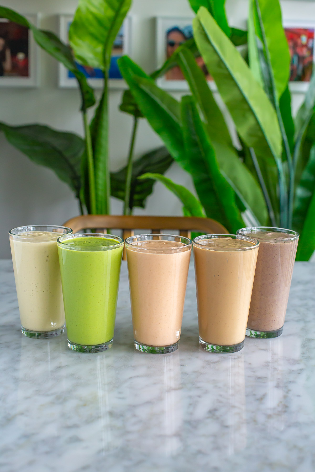 Five glasses each filled with a blended meal prep smoothie pack.