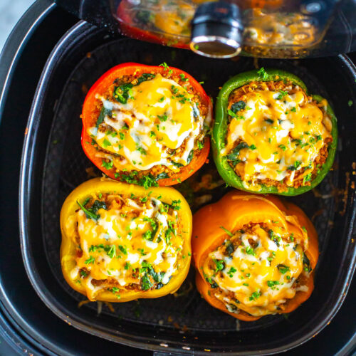 Four cooked air fryer stuffed peppers in an air fryer.