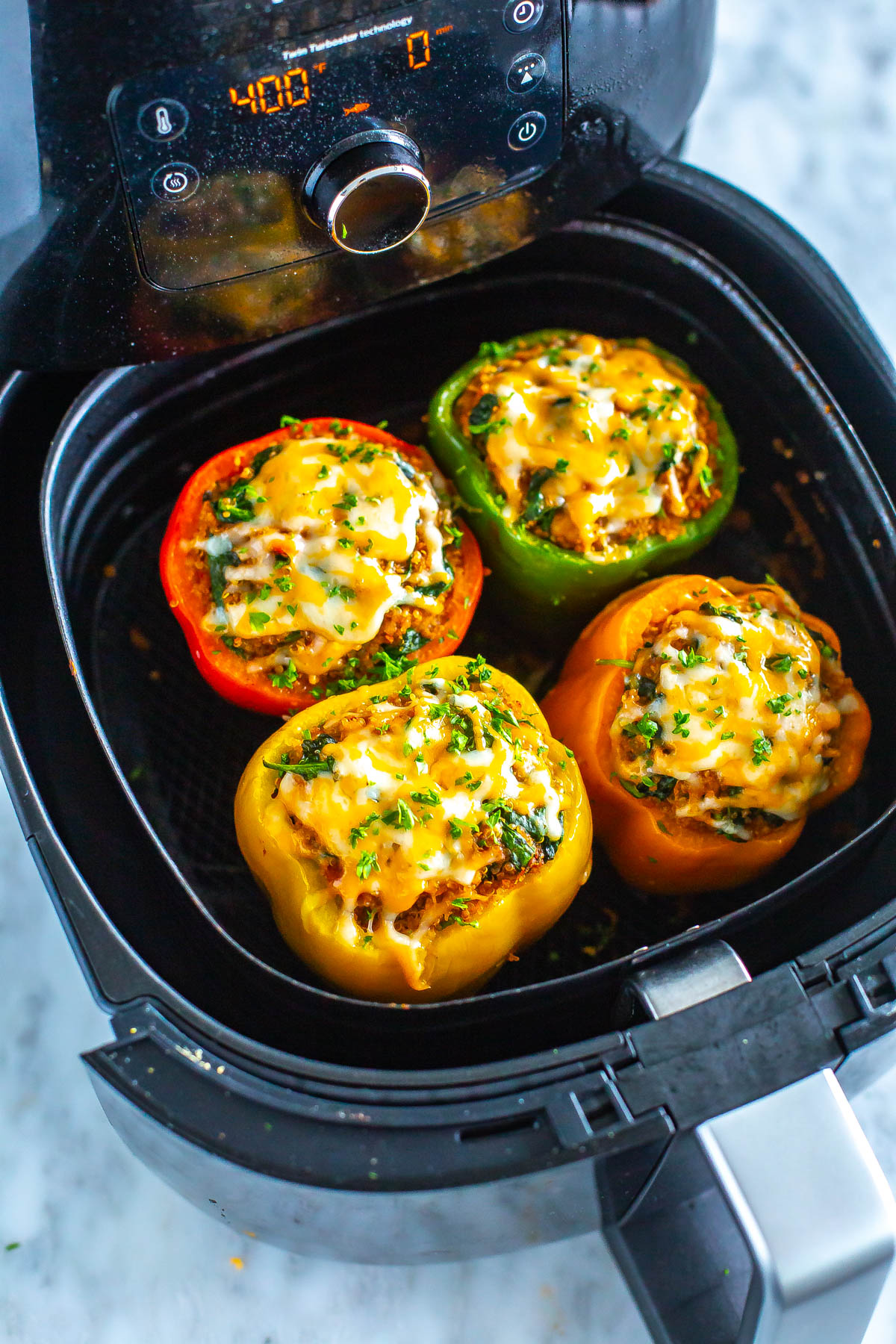 An air fryer with cooked stuffed peppers inside.
