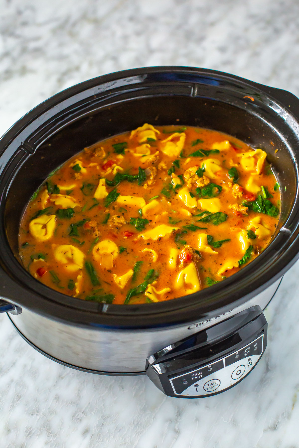 A slow cooker filled with crockpot tortellini soup/