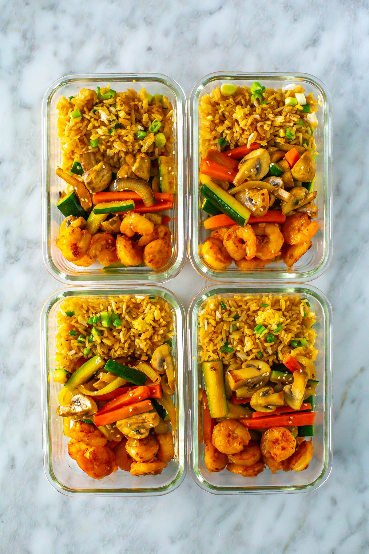Four different meal prep containers, each with a serving of hibachi shrimp.