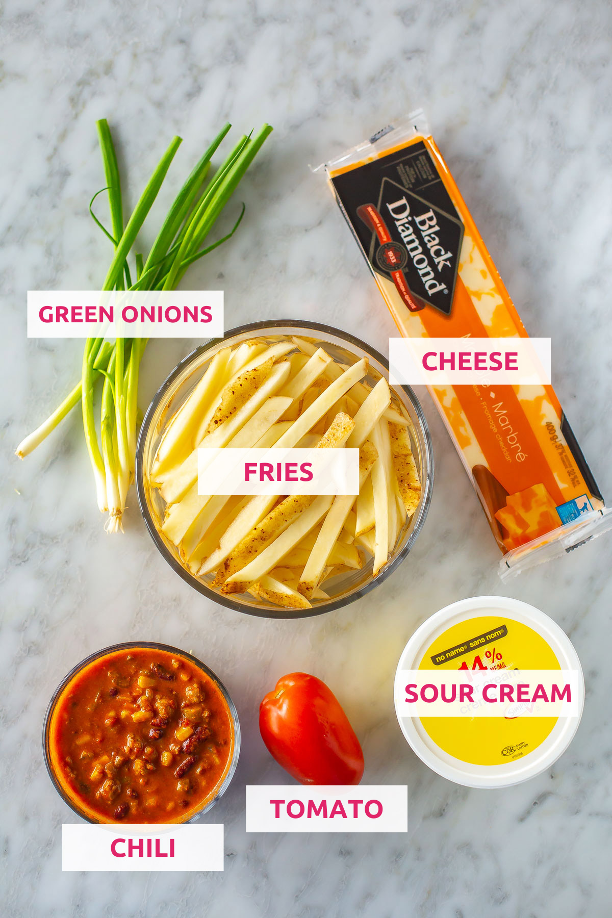 Ingredients for chili cheese fries: chili, tomato, sour cream, green onions, fries and cheese.