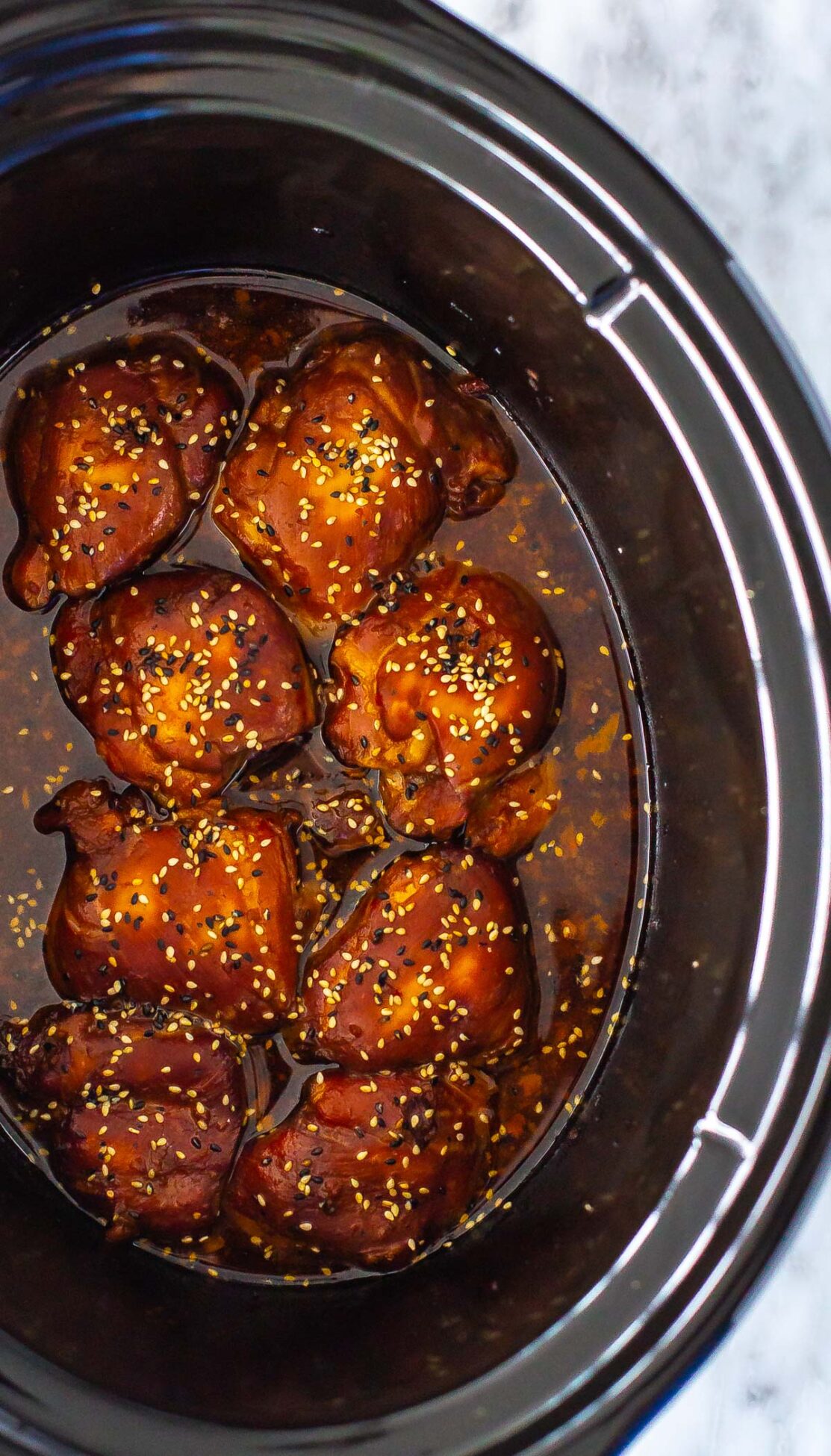 A slow cooker with honey garlic chicken thighs inside.