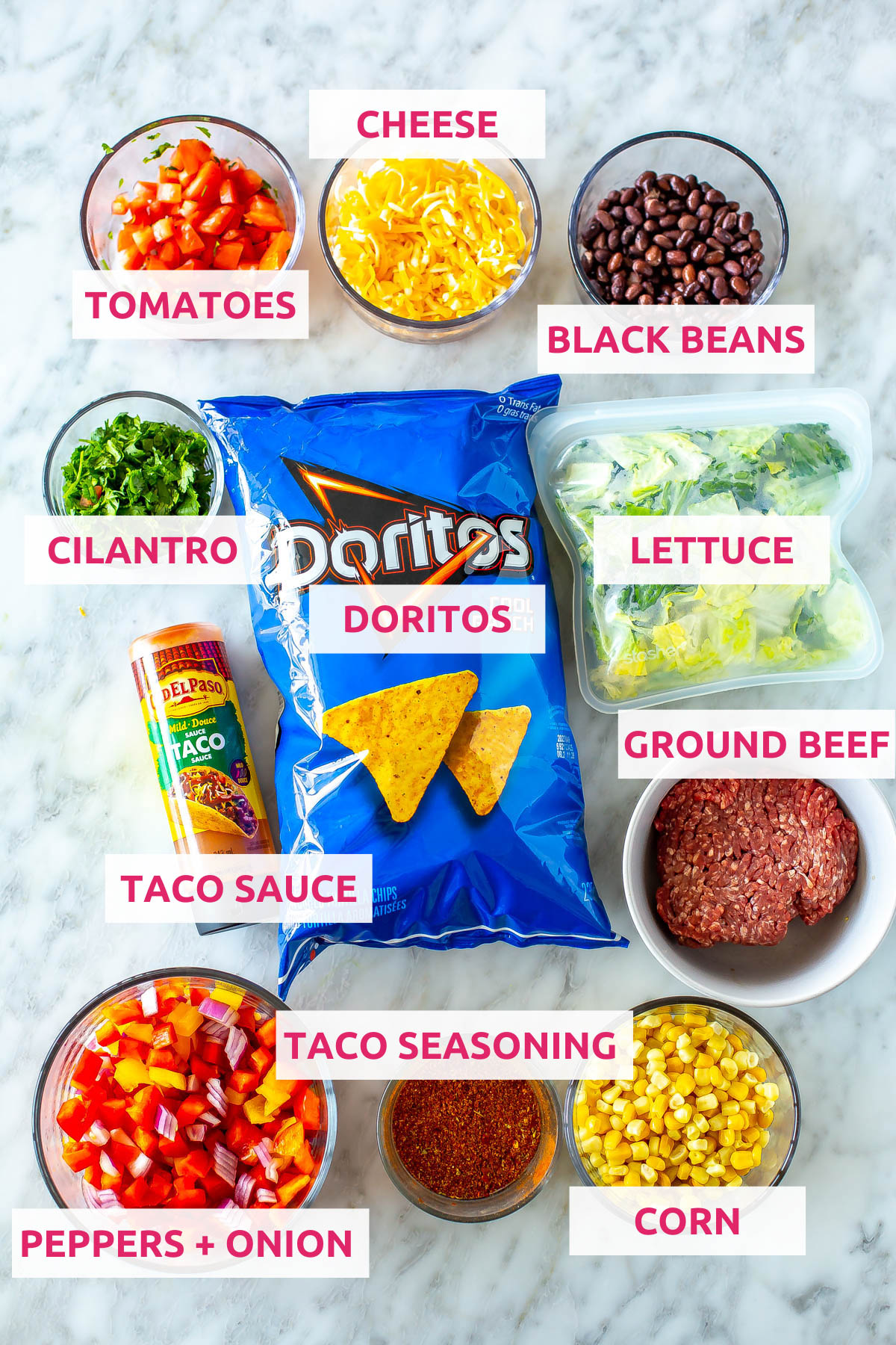 Ingredients for dorito taco salad: doritos, black beans, cheese, tomatoes, cilantro, lettuce, ground beef, taco sauce, peppers, red onion, taco seasoning and corn.