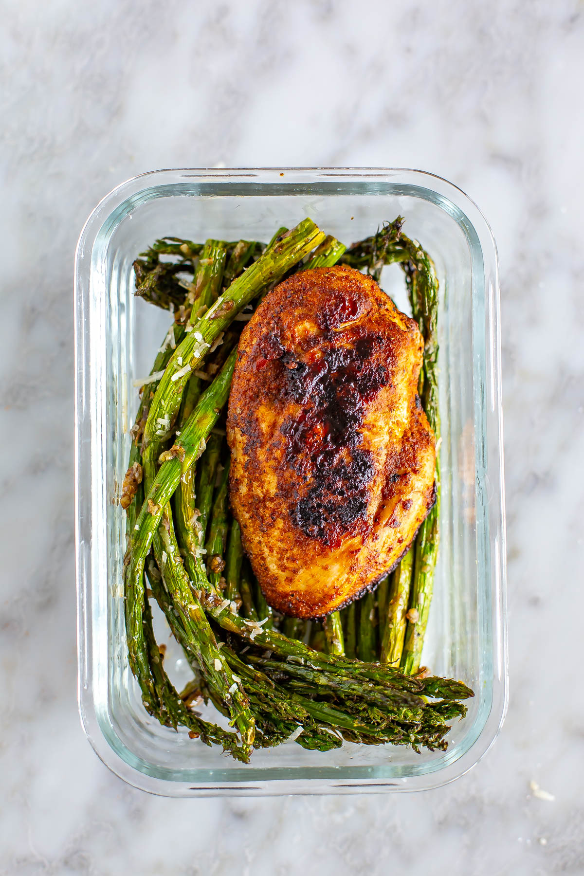 A meal prep container with air fryer asparagus and a chicken breast.