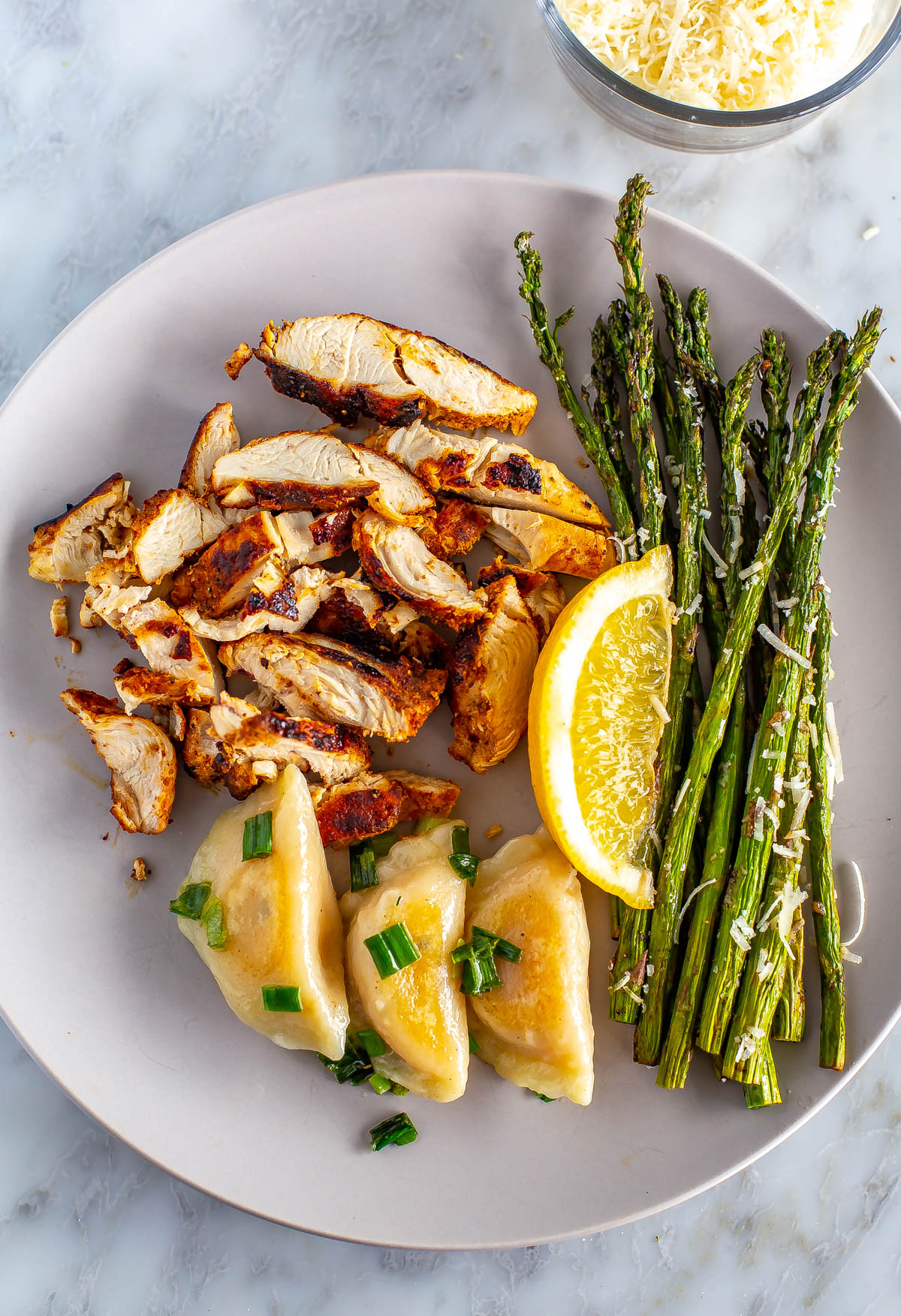 A plate with air fryer asparagus served with cut up chicken breasts and dumplings.