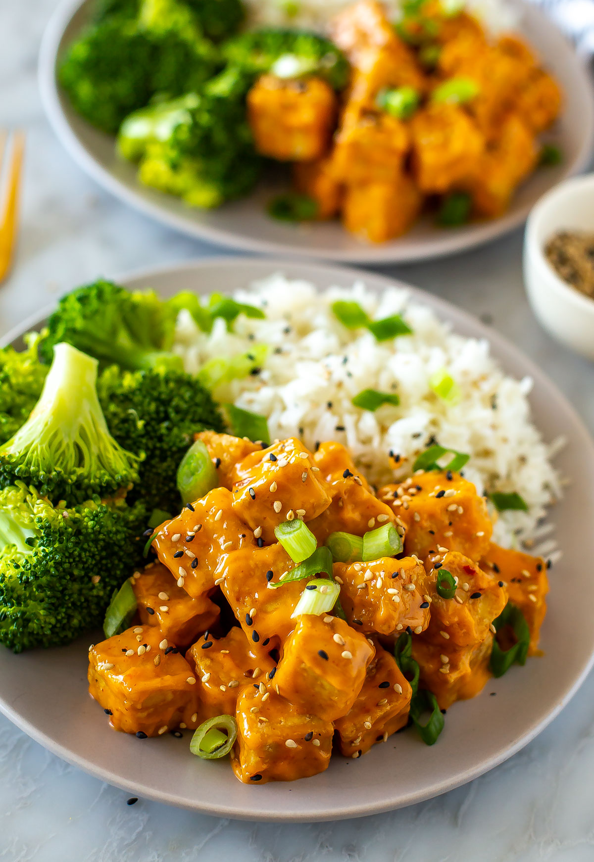 A close-up of a plate of air fryer tofu with rice and broccoli on the side.