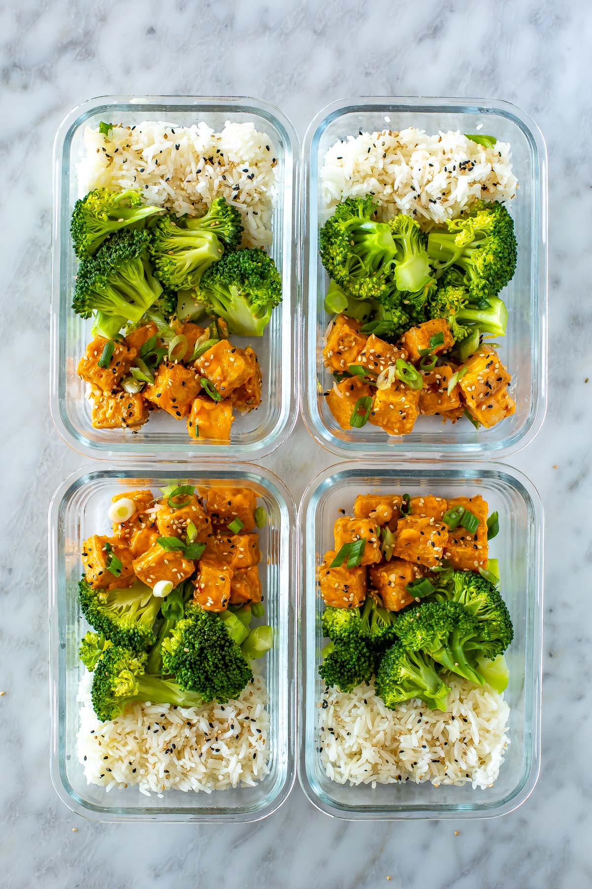 Four meal prep containers, each with rice, broccoli and air fryer tofu.