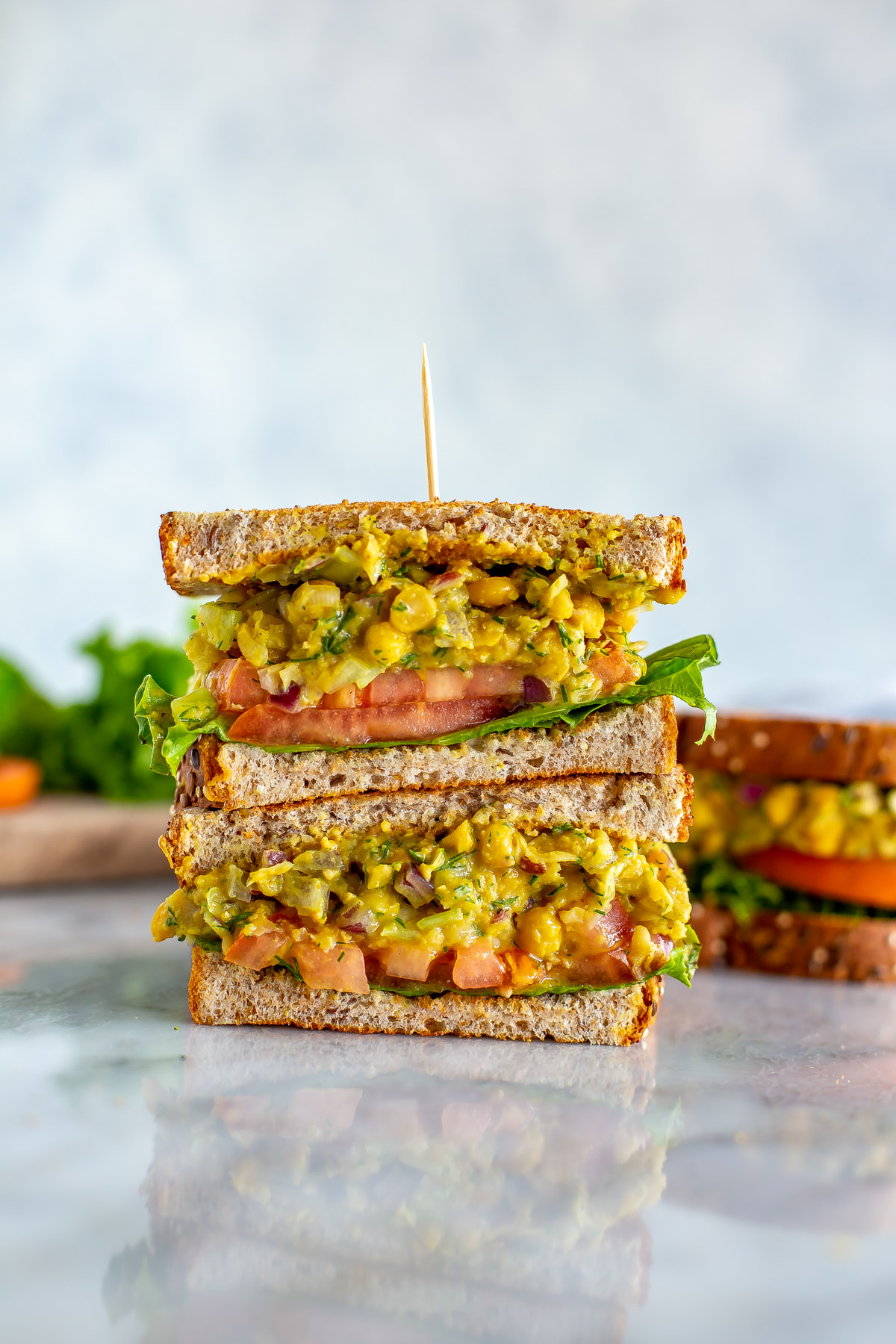 Two halves of a chickpea tuna salad sandwich stacked together with a toothpick.
