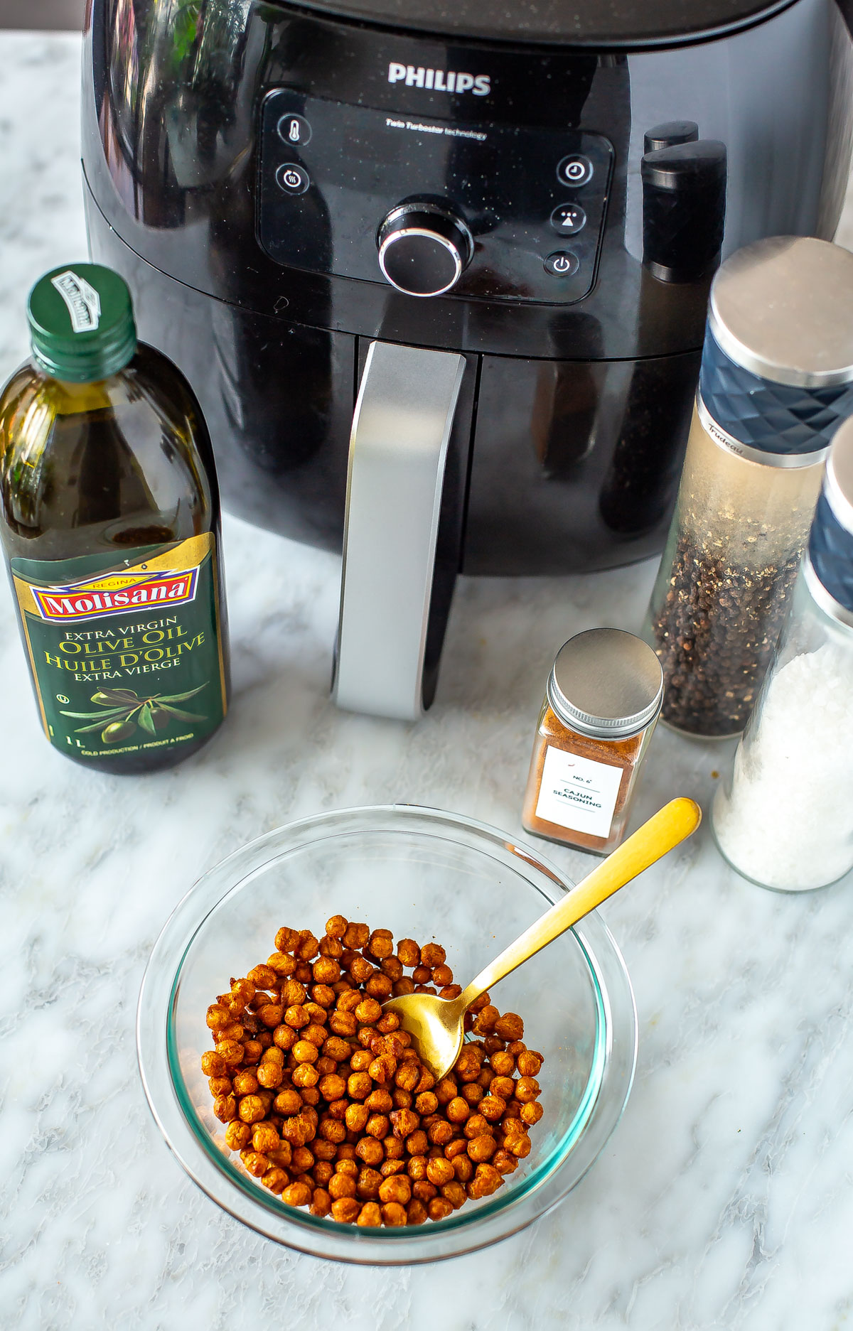 An overhead shot of an air fryer with crispy chickpeas in a bowl in front of it.