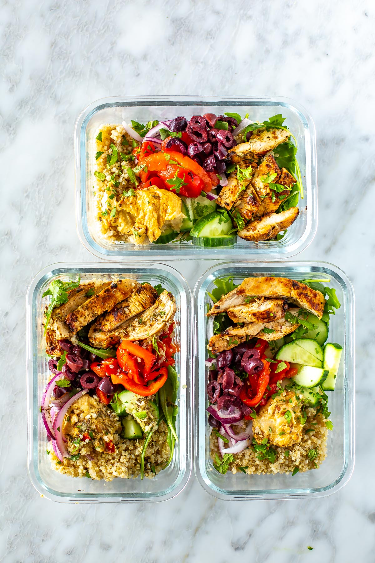 Three Mediterranean bowls stored in glass meal prep containers.