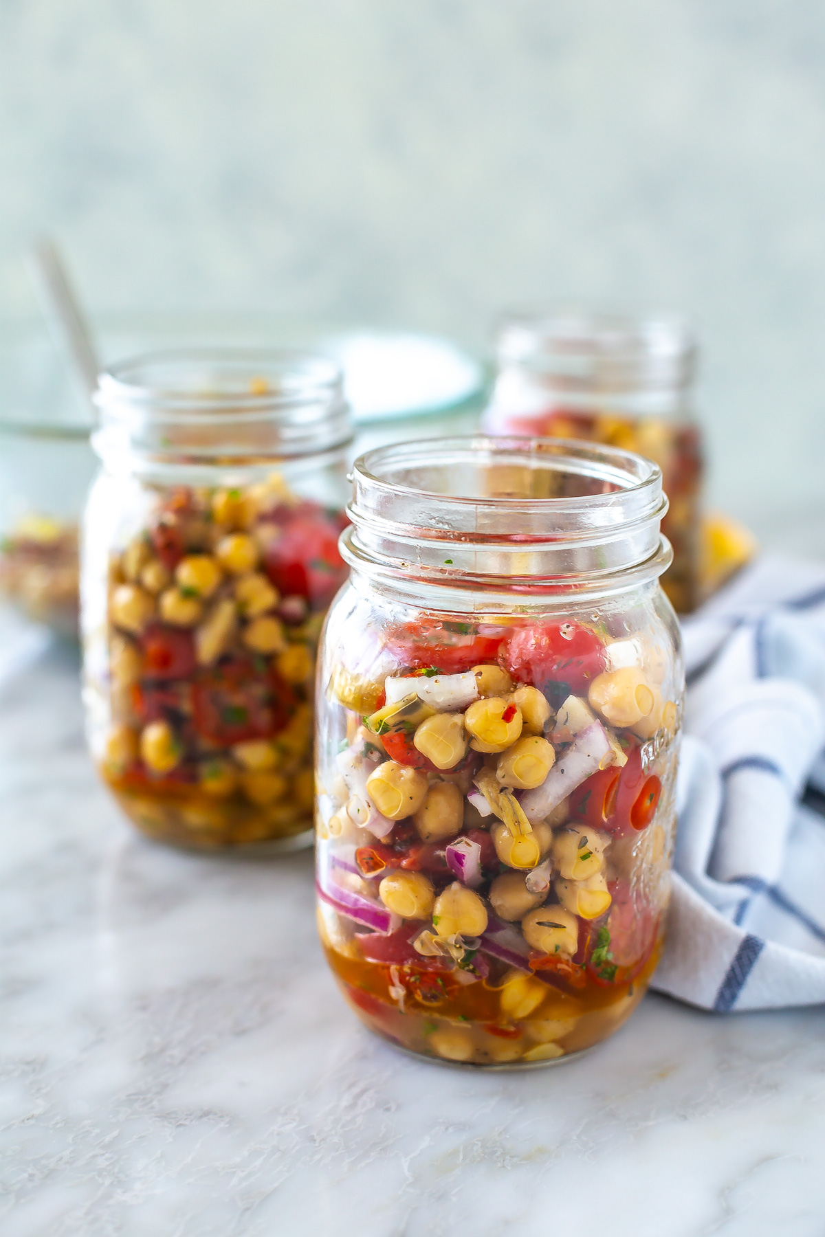 Two mason jars filled with Mediterranean chickpea salad.
