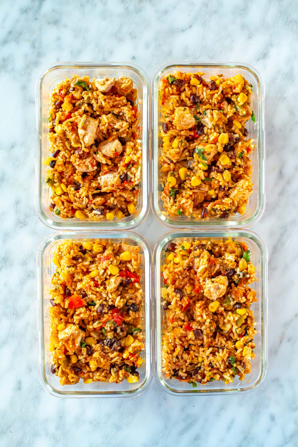 Four meal prep containers, each with a serving of Instant Pot chicken burrito bowls. 