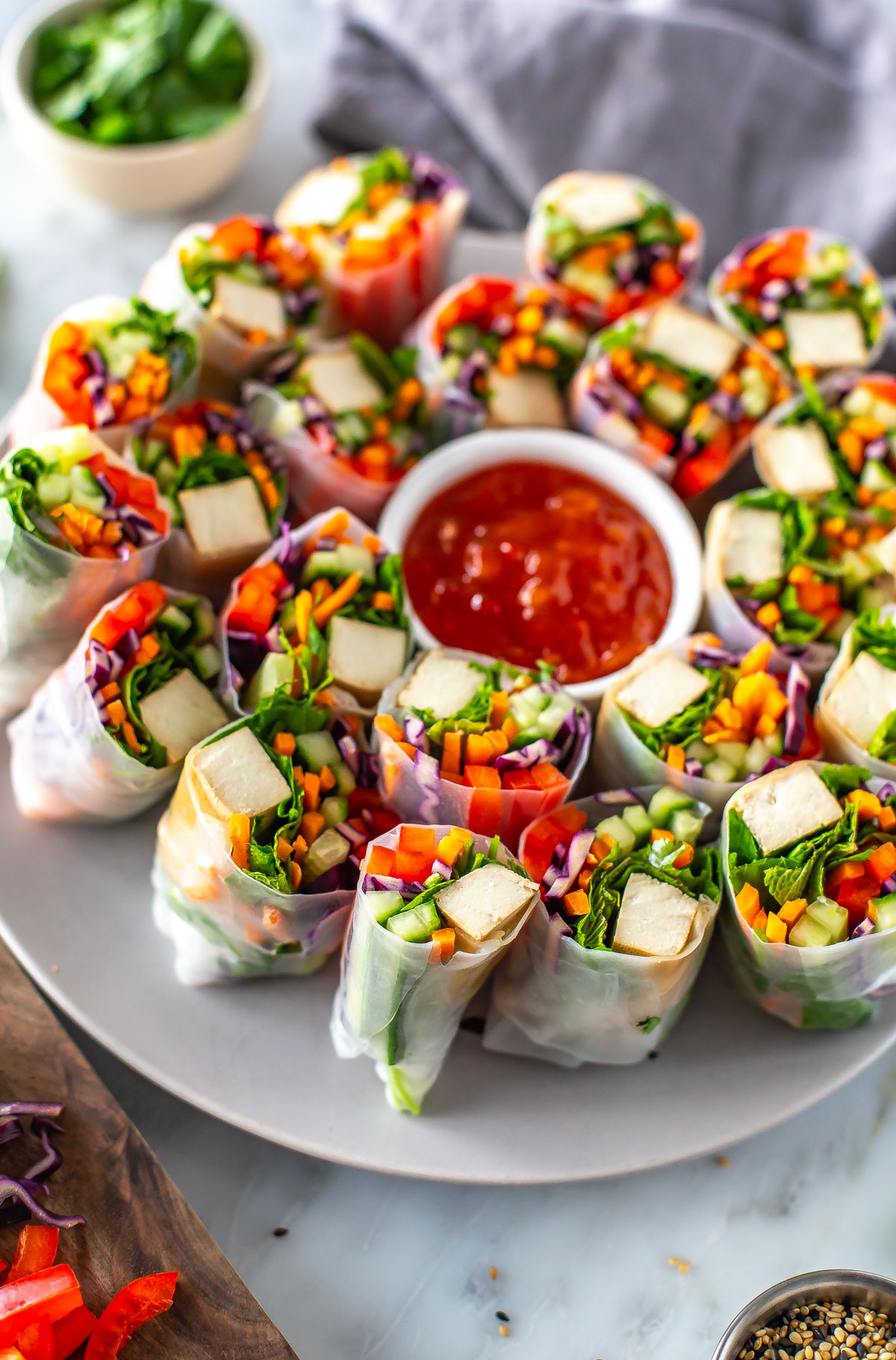A plate of summer rolls with a bowl of sweet chili sauce in the middle.
