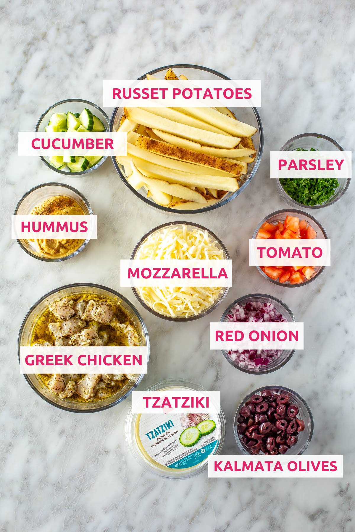 Ingredients for Greek fries: russet potatoes, cucumbers, hummus, Greek chicken, mozzarella, olives, tzatziki, red onion, tomato and parsley.