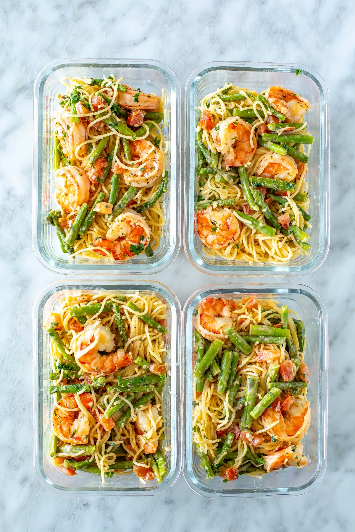 Four meal prep containers, each with a serving of Olive Garden Shrimp Scampi.