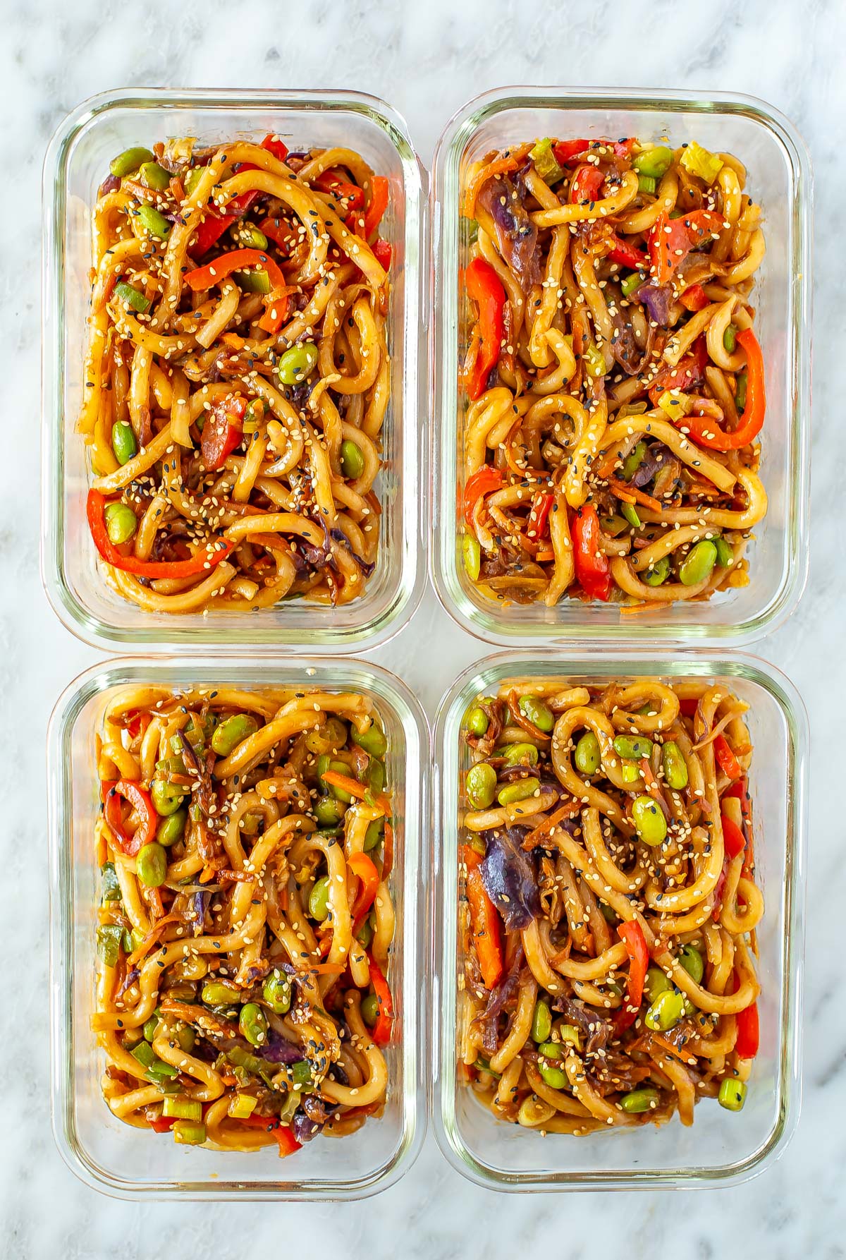 Four meal prep containers, each with a serving of udon noodles.