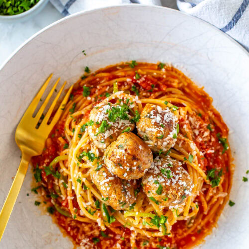 Baked turkey meatballs on a plate of pasta and zucchini.