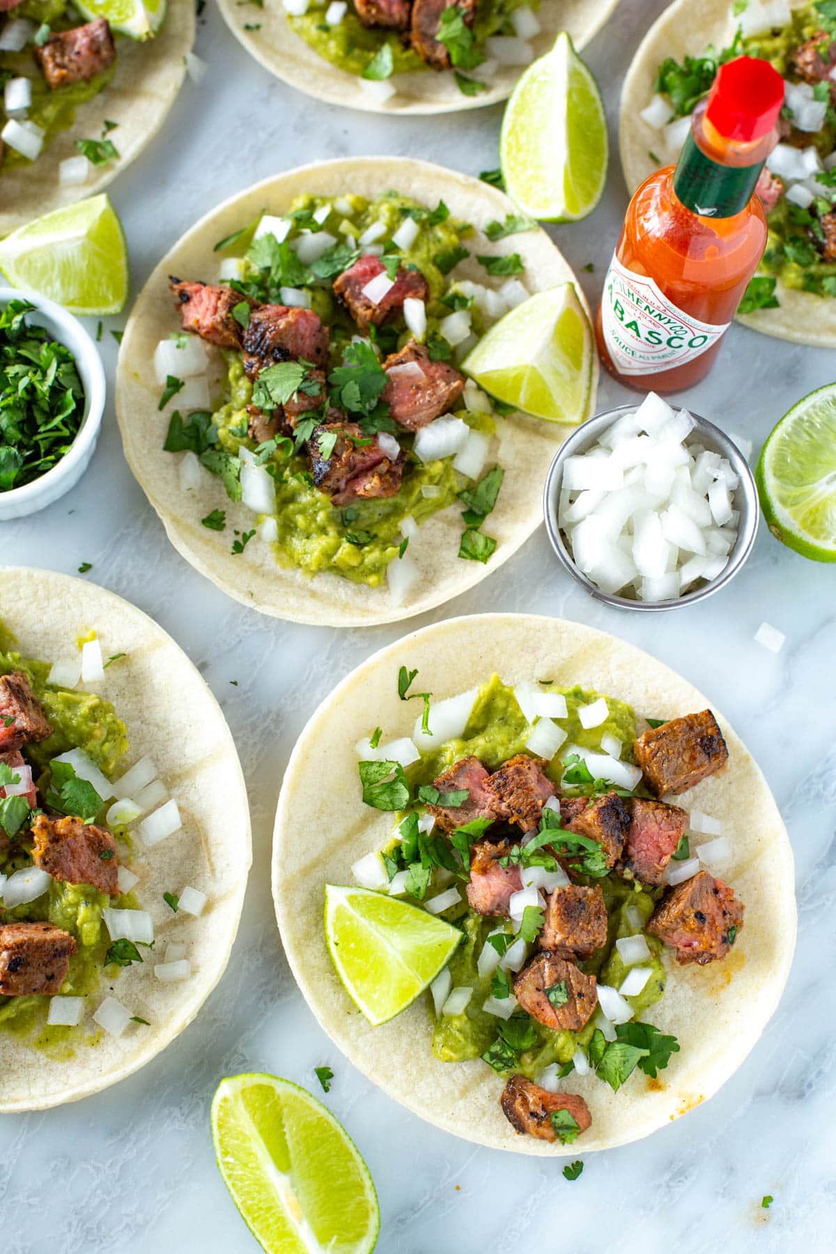 Carne asada tacos garnished with lime wedges and cilantro