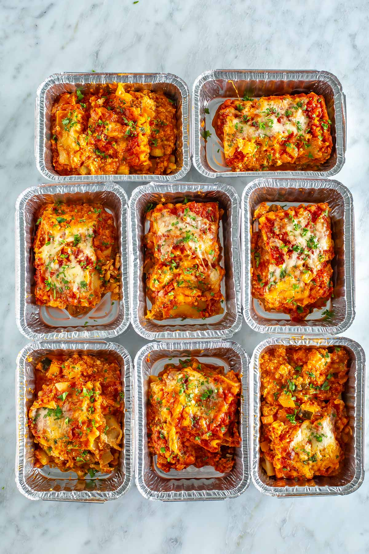 8 slices of vegetarian lasagna in individual aluminum food containers.