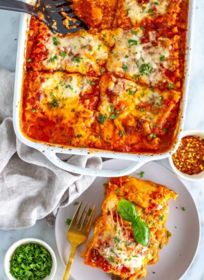 A vegetable lasagna in a casserole dish with a piece plated.