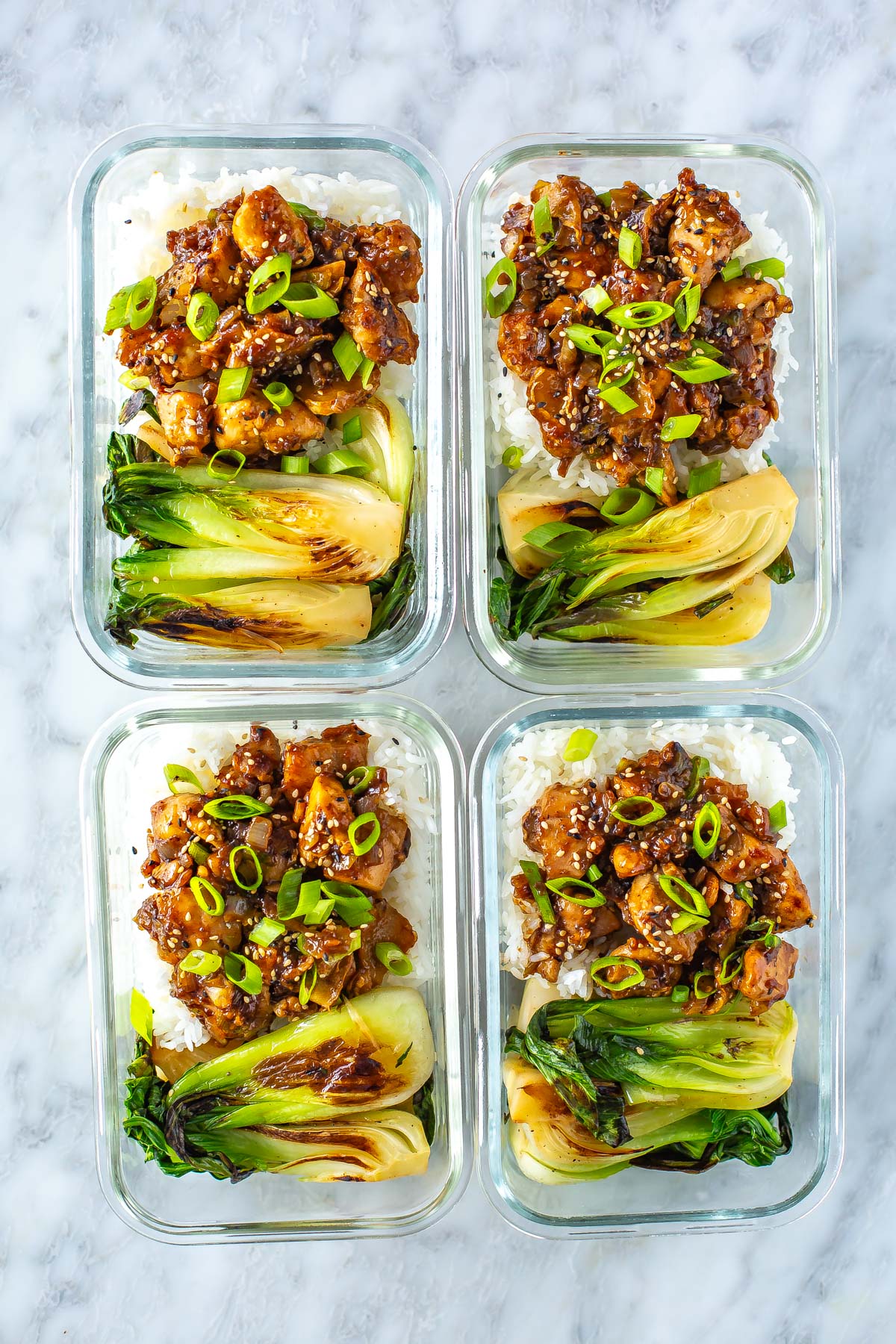4 meal prep containers, each with a serving of ginger chicken, bok choy and rice.